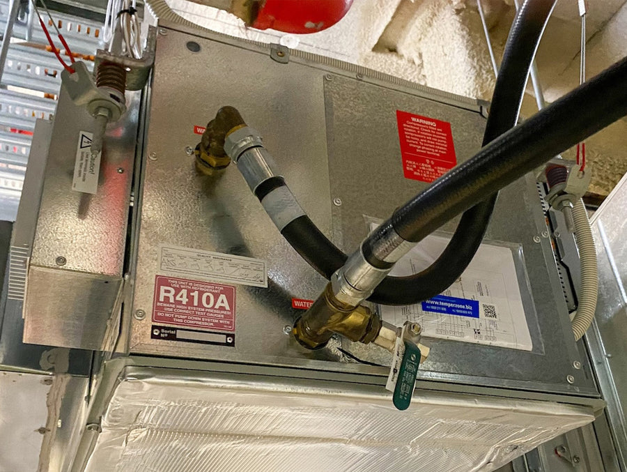 Metallic HVAC component with pipes and labels in an industrial setting